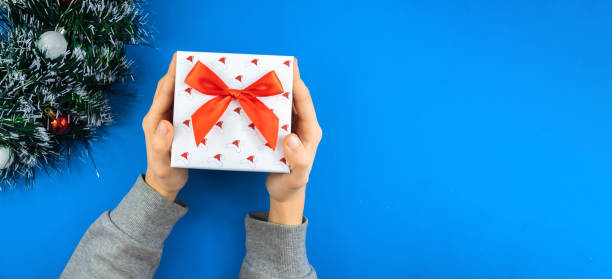 istock Festive banner on a blue background, a man holding a beautiful gift box with a bow, copy space or layout 1287253786