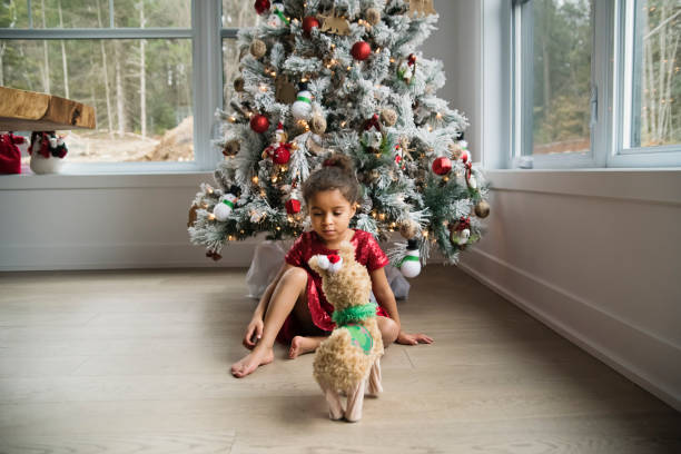 Mixed-race little girl day dreaming in front of the Christmas tree.