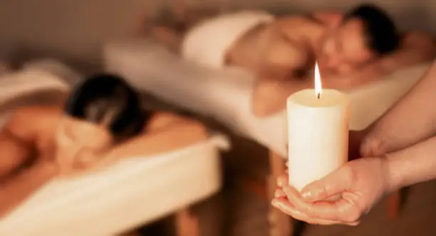 Photo of Aromatherapy, hot oil massage. Aromatherapy candle in hands of a massage therapist before a hot oil massage for a beautiful couple