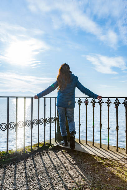 istock Woman with a blue down jacket on the railing at a lake 1287255383