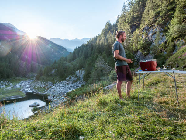 男は彼のバンの外のポータブルバーベキューで料理します, 山の景色 - switzerland european alps ticino canton scenics ストックフォトと画像