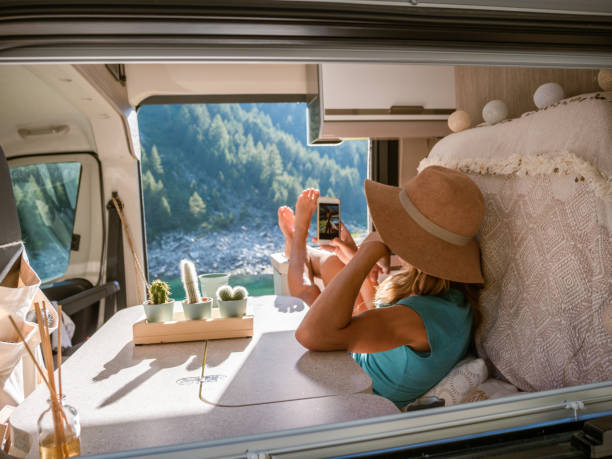 istock Happy woman uses her phone inside a van overlooking alpine lake 1287257080