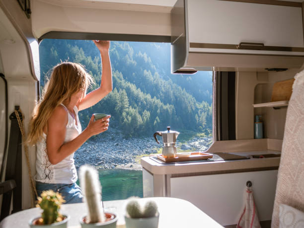 Woman enjoys fresh Italian coffee from her van She contemplates the beautiful landscape in the Swiss Alps, alpine lake and mountain in distance. Switzerland adaptation to nature stock pictures, royalty-free photos & images