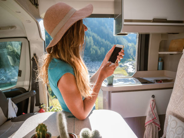 istock Happy woman uses her phone inside a van overlooking alpine lake 1287257643