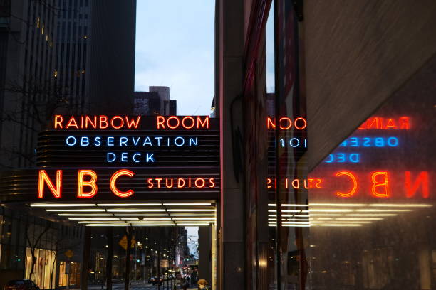 The entrance to NBC with its reflection inverted at night in New York at Rockefeller Center.\nA symbol of the complexity of information work with the play of oppositions, paradoxical points of view, opposing personalities within the editorial staff.