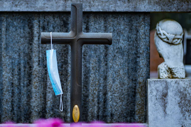 istock Coronavirus death. Face mask on a cross in the cemetery. 1287258859