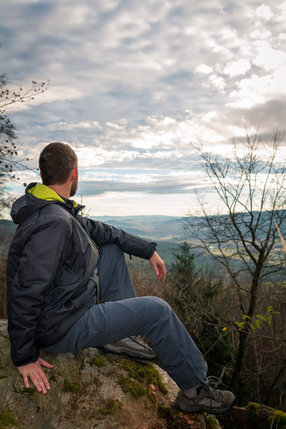 istock Young man sitting on mountain in autumn forest from side. Czech landscape 1287259046