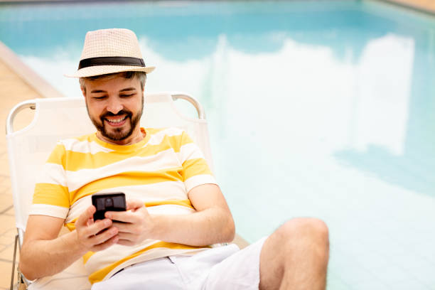 istock Man relaxin near the pool and using cell phone 1287260792