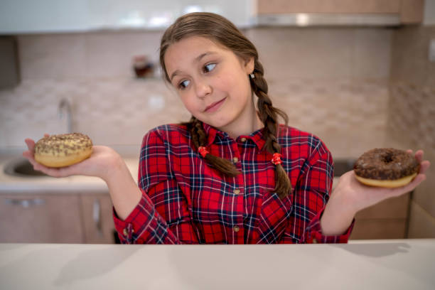 istock Cute kid girl holding donuts 1287264561
