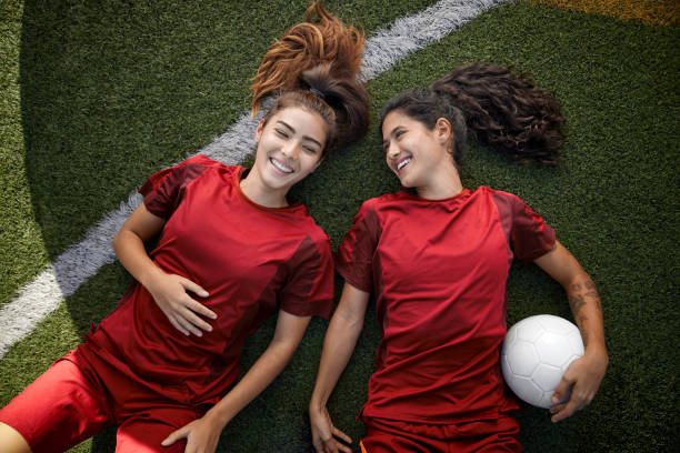 풀밭에 누워 휴식을 취하는 행복한 여성 축구 팀원 두 명 - playing field sport friendship happiness 뉴스 사진 이미지