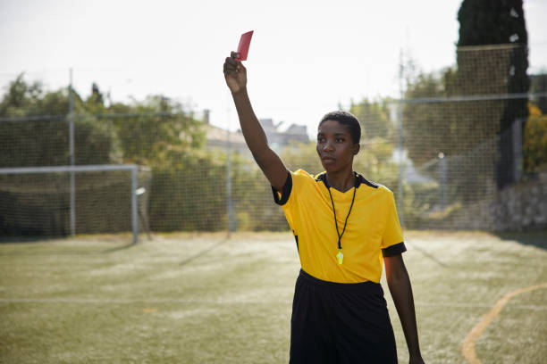 African-american female referee holding red card in yellow uniform Portrait of african-american female referee holding red card in yellow uniform referee stock pictures, royalty-free photos & images