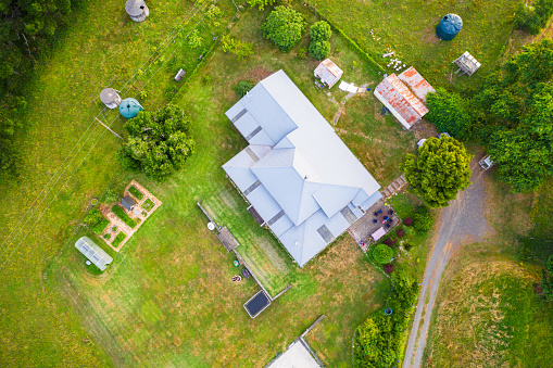 An aerial view from directly above a house in the country, with outbuildings and a driveway.