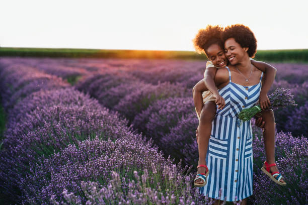 Young and carefree Afro daughter and her mother spending the day at lavender field lavender lavender coloured bouquet flower stock pictures, royalty-free photos & images