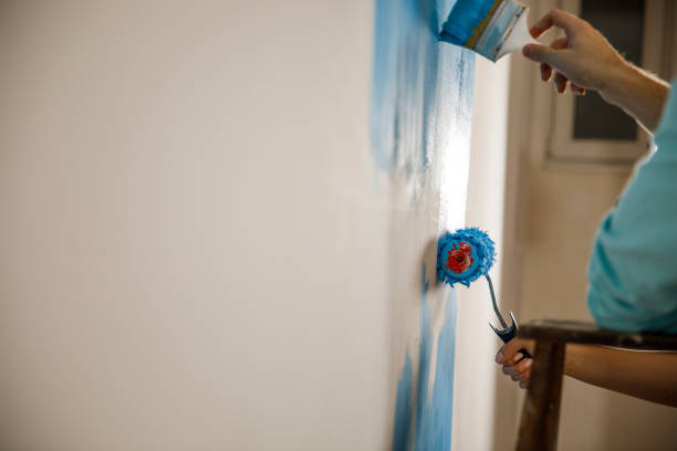 istock Using a paintbrush and paint roller to paint the walls 1287270868