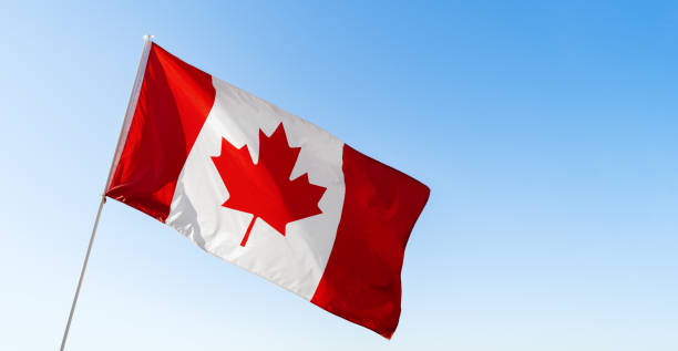 istock Flag of Canada waving against blue sky 1287274754