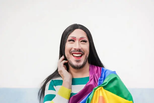 Portrait of cheerful drag queen at gay pride parade with rainbowflag - LGBTQI
