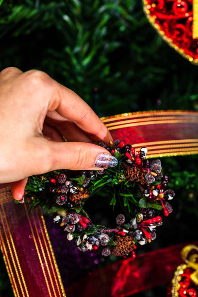 istock Decorating Christmas tree, hand putting Christmas decorations on fir branches. Christmas hanging decorations. 1287278717