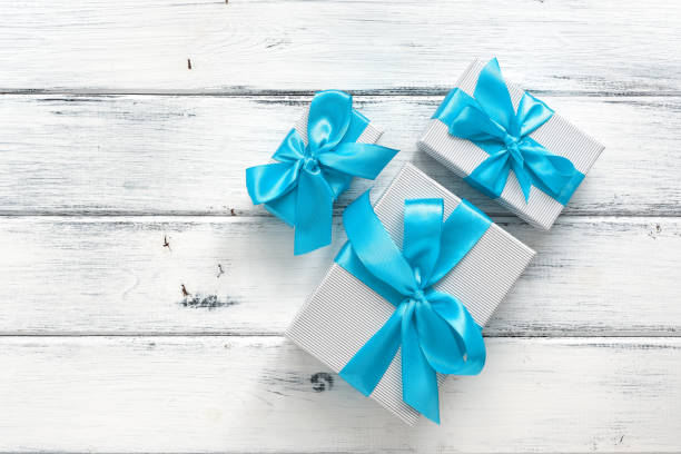istock Gift boxes with blue ribbon on a white wooden background. Top view, flat lay. 1287279083