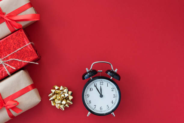 istock flat lay of black round clock and tree giftboxes with ribbons on left lie on red background, copy space for text. 1287279996