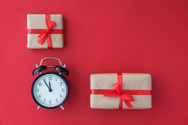 istock flat lay of black round clock and two giftboxes with ribbons lie on red background, 1287280333