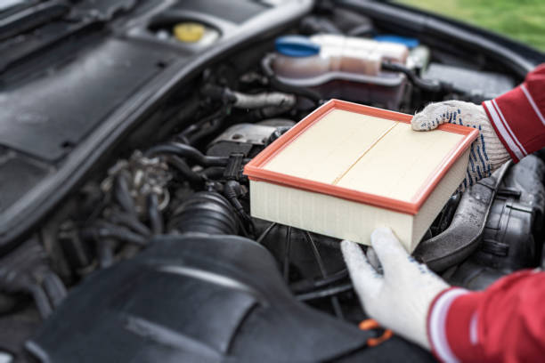 Comparison new and used air filter for car with engine background. Clean and dirty cabin pollen air filter for a car. Technician is changing new air filter for car. Engine air filter.