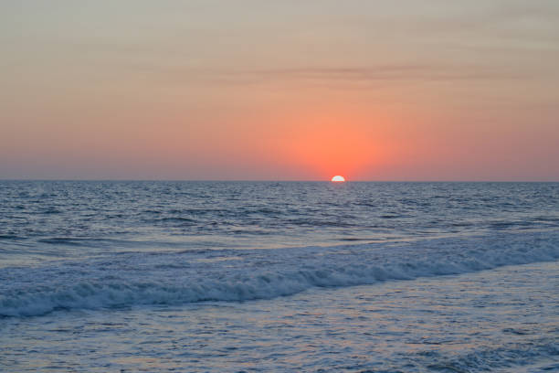 istock Orange sun halfway disappeared into the ocean. 1287287103