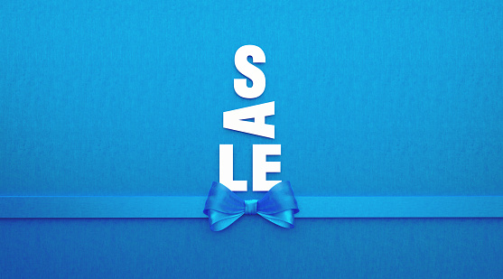 Sale text forming a Christmas tree and is tied with blue ribbon on blue background. Horizontal composition with copy space. Directly above. Great use for Christmas related sale concepts.