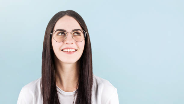 istock Young woman posing isolated over blue wall background, watching to the copyspace in upper right corner 1287293071