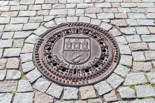 Prague, Czech Republic - July 10, 2020: Prague manhole cover of sewage well, cast iron sewer cover.