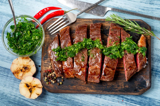 steak de bœuf juteux tranché avec sauce chimichurri et épices sur planche de bois. - chimichurri horizontal beef steak photos et images de collection