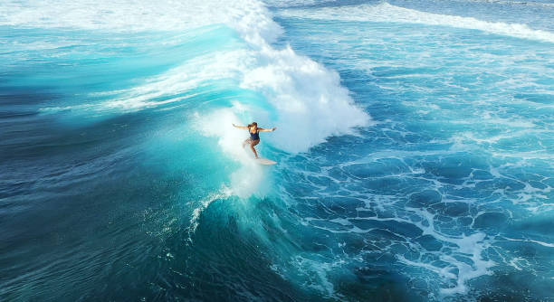 Surfer woman riding on the blue ocean Surfer woman riding on the blue ocean breaking wave stock pictures, royalty-free photos & images