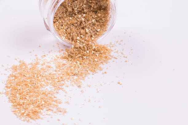 istock Background with gold glossy eye shadow. Glass jar with gold glossy eye shadow on white background. Horizontal image. 1287303592