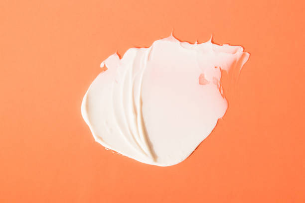 istock A beautiful light cream smear on a orange background. Smear, mask, cream, light, face, orange background. Top view. 1287304418