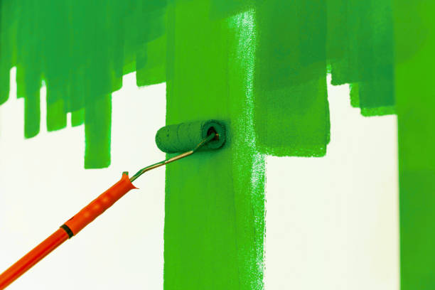 Green strips of blue paint on a white wall and red roller. Home renovation, texture. Copy space, top view.