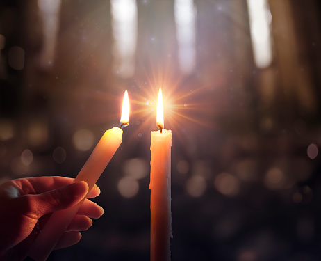 Concepto de esperanza desenfocada - La mano encendiendo una vela con llama brillante y luces borrosas photo