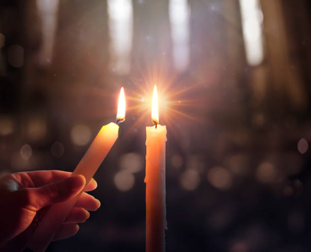 concepto de esperanza desenfocada - la mano encendiendo una vela con llama brillante y luces borrosas - luz de vela fotografías e imágenes de stock