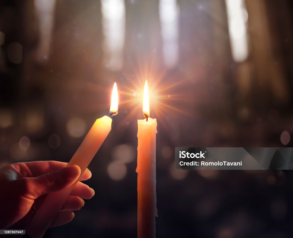 Defocused Hope Concept - Hand Igniting A Candle With Shining Flame And Blurry Lights Sharing Concept - Hands Holding Candle With Shining Flame And Blurry Lights Candle Stock Photo