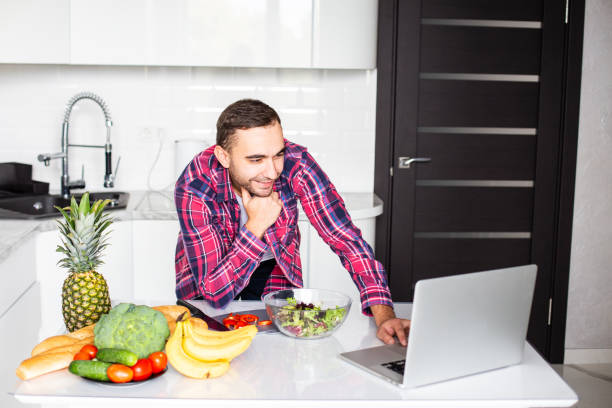 istock Handsome caucasian man cooking on kitchen with laptop on table 1287309412