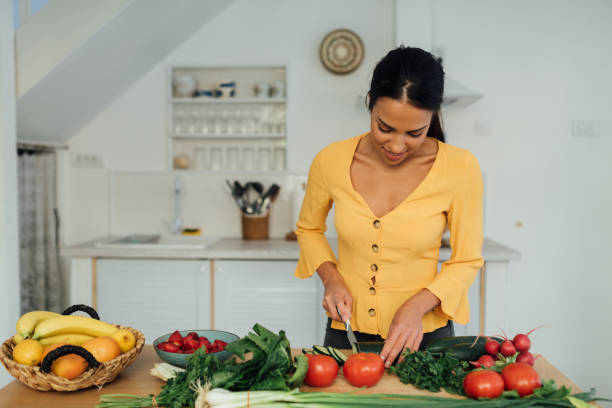 istock Beautiful young woman preparing food in her kitchen 1287309507