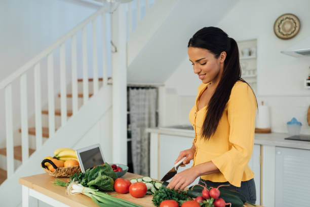 istock Beautiful young woman preparing food in her kitchen 1287310091