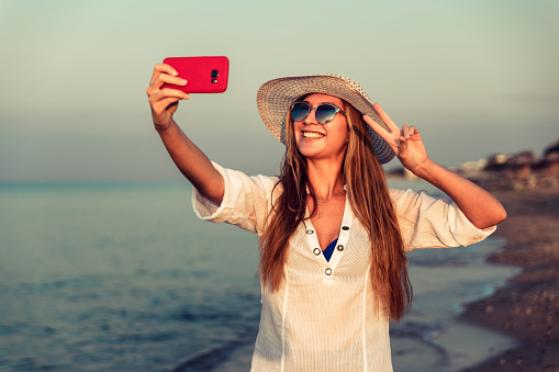 Young smiling woman taking selfie on the beach