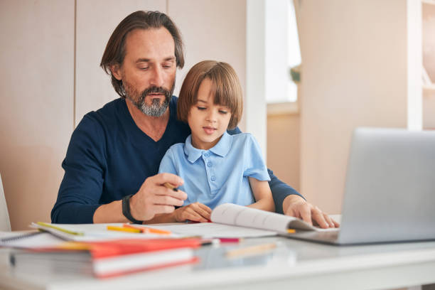 istock Caring father helping his child to cope with homework 1287312522