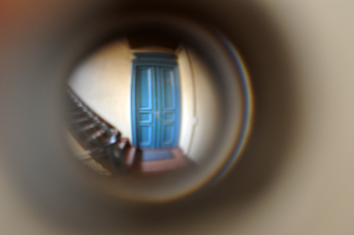 view through the peephole at the blue door in the corridor to the staircase