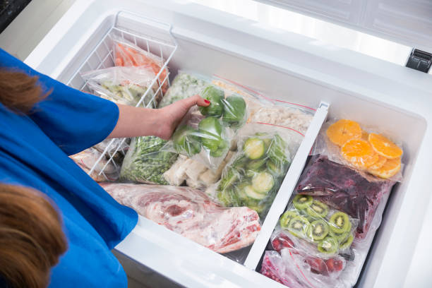 ピーマンを冷蔵庫に入れる女性 - 冷凍食品 ストックフォトと画像