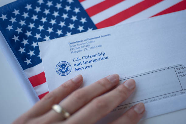 Hand touching Letter (Envelope) from USCIS on  flag of USA background. Close up view. stock photo