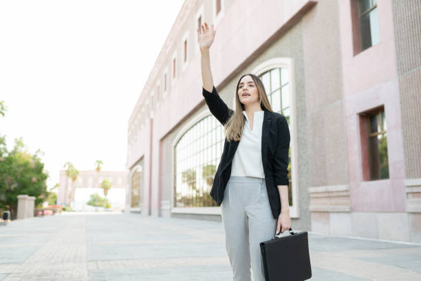 istock Woman with a busines suit calling a taxi cab 1287317825