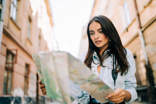 istock Young female tourist with map visiting city and looking around 1287318457