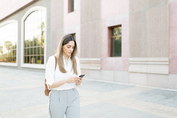 istock Pretty female worker in her 30s walking while sending a text 1287318518