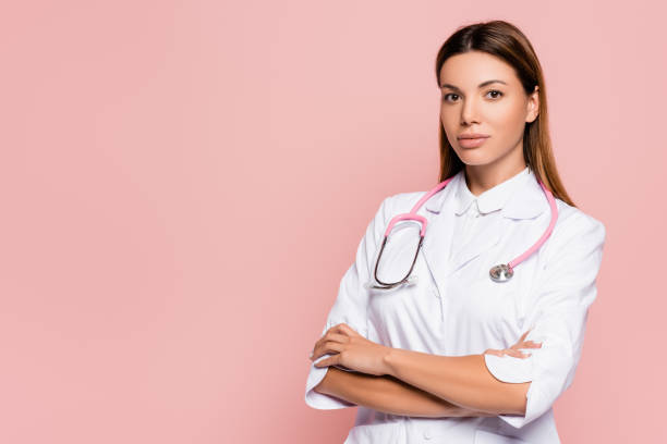 istock Young doctor in white coat and stethoscope looking at camera isolated on pink 1287325782