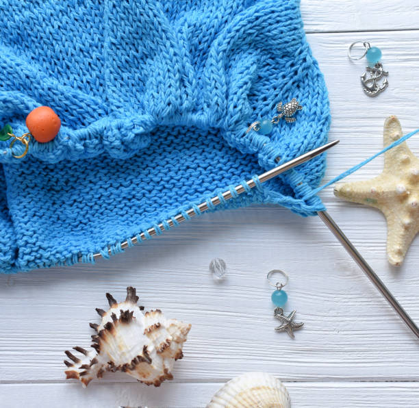 A knitted fabric from blue cotton yarn on a white background in a marine theme with sea shells.